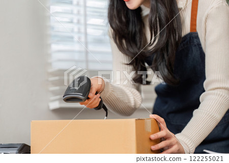 Woman utilizing a barcode scanner to efficiently deliver merchandise in a modern workspace 122255021