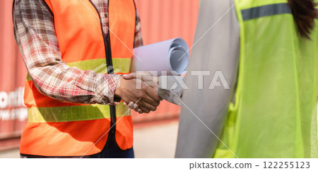 Construction professionals shaking hands on-site, discussing project plans and collaboration 122255123