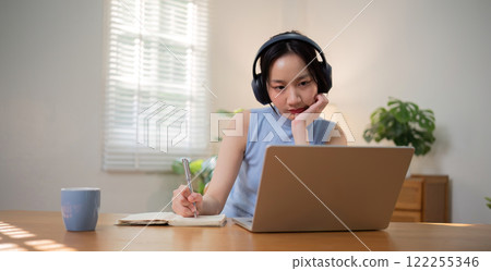 Asian college student who is bored Sitting in front of a laptop studying online through a video calling program on a laptop at home. 122255346