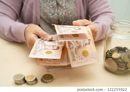 Retired Asian elderly woman counting coins money and worry about monthly expenses and treatment fee payment. Retired Asian elderly woman counting coins money and worry about monthly expenses and treatment fee payment. 122255922