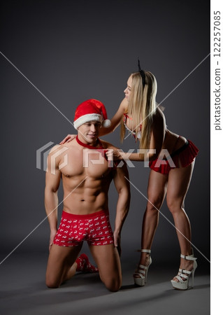 Couple engages in playful roleplay with festive attire in indoor setting 122257085