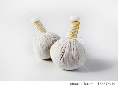 a traditional Thai herbal compress wrapped in white cloth, placed on a wood top table in spar room a traditional Thai herbal compress wrapped in white cloth, placed on a wood top table in spar room 122257919
