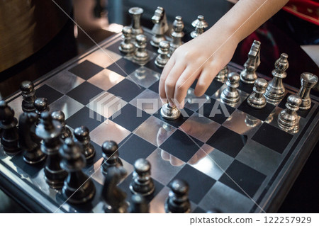 A hand reaching for a chess pawn, about to start a new game A hand reaching for a chess pawn, about to start a new game 122257929
