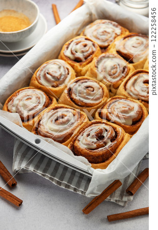 Freshly baked cinnamon rolls drizzled with icing in a baking pan 122258456