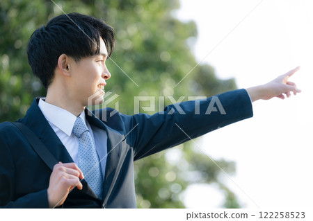 A young man who looks like a new graduate wearing a suit outdoors pointing at his goals and future 122258523