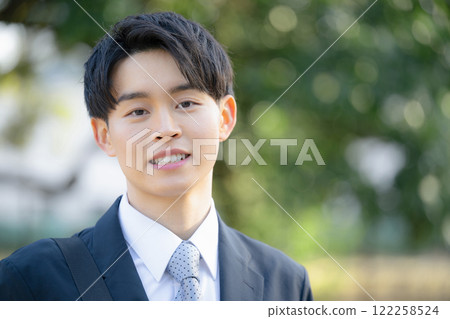 一個年輕人的春夏特寫，他看起來像個剛畢業的年輕人，穿著西裝在戶外看著相機 122258524