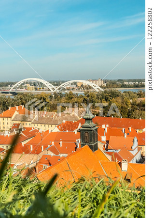 cityscape of Novi Sad from the historic vantage point of Petrovaradin, where ancient towers and charming streets intertwine with the gentle flow of the Danube. 122258802