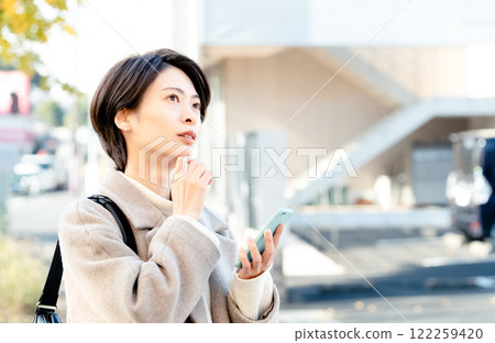 一個女人看著智能手機在戶外 122259420