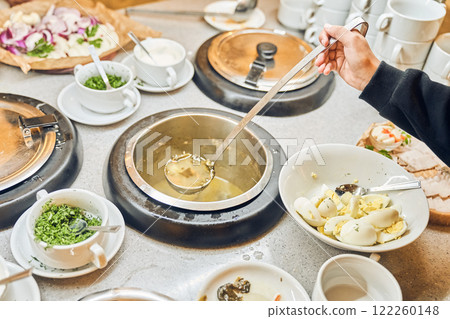 The hand holds a ladle with liquid soup. A delicious hot dish in cups with a variety of fresh vegetables and tender meat, simmered in a spicy broth. High quality photo The hand holds a ladle with liquid soup. A delicious hot dish in cups with a variety of fresh vegetables and tender meat, simmered in a spicy broth. High quality photo 122260148