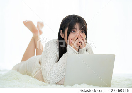 A Japanese woman lying face down and operating a computer A Japanese woman lying face down and operating a computer 122260916
