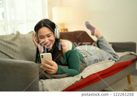 Cheerful young woman listening to music or watches a video on her smartphone 122261288