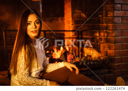 Woman relaxing at fireplace. Winter home. 122261474