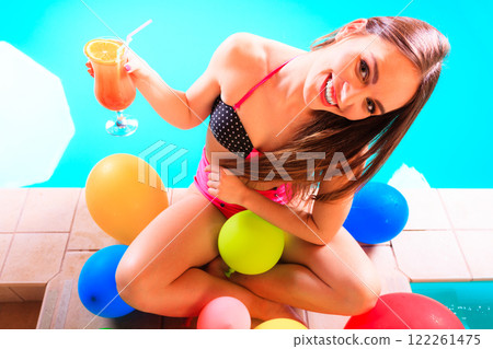 Happy woman with balloons and cocktail at poolside Happy woman with balloons and cocktail at poolside 122261475