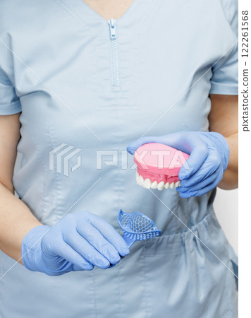 Dentist with a dental pliant impression tray and a layout of the human jaw. 122261568