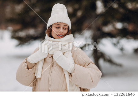 Happy smiling young woman portrait dressed coat scarf hat and mittens enjoys winter weather at snowy winter park 122261640