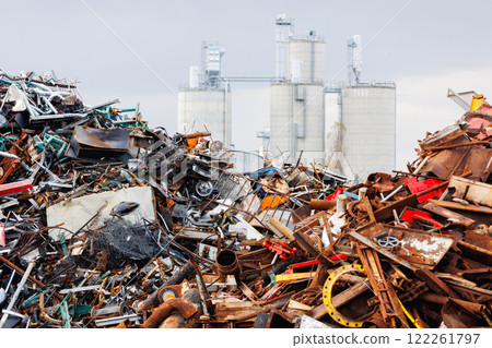 Scenic metal scrap yard huge pile of rusty metal parts disposal waste at junkyard recycling site against industrial factory plant area at Germany. Scrapyard waste management industry background 122261797
