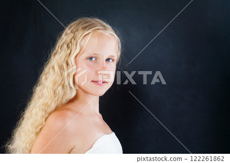 Beautiful blond young girl with long healthy curly hair on black background, fashion portrait 122261862