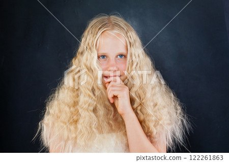 Thinking child with blond long wavy hair looking at camera on black background, fashion portrait 122261863