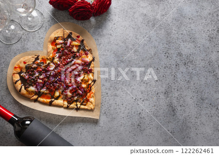 Food for Valentine's Day. Romantic dinner with red wine, heart shaped sweet homemade pizza on gray background. View from above. Copy space. 122262461