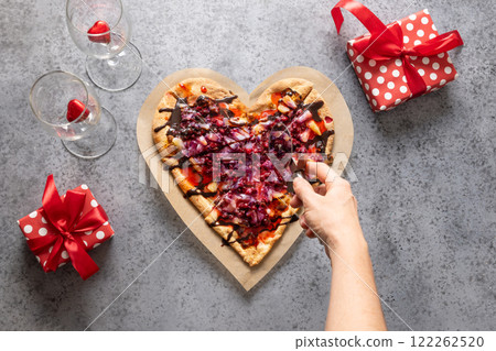 Food for Valentine's Day. Woman cutting heart shaped sweet pizza for romantic dinner on gray background. View from above. 122262520
