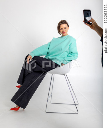 Portrait beautiful woman of model appearance. Girl in mint jumper, black trousers, red shoes on grey background. Pretty female with trendy makeup posing in studio. Vertical photo. Portrait beautiful woman of model appearance. Girl in mint jumper, black trousers, red shoes on grey background. Pretty female with trendy makeup posing in studio. Vertical photo. 122263511
