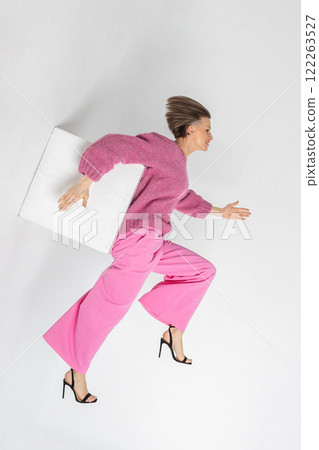 Portrait beautiful woman of model appearance. Girl in pink sweatshirt and trousers on grey background. Pretty female with trendy makeup posing in studio. Vertical photo. Portrait beautiful woman of model appearance. Girl in pink sweatshirt and trousers on grey background. Pretty female with trendy makeup posing in studio. Vertical photo. 122263527