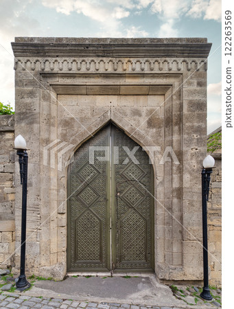 Historic ornate door with intricate designs in an ancient stone wall under a cloudy sky Historic ornate door with intricate designs in an ancient stone wall under a cloudy sky 122263569
