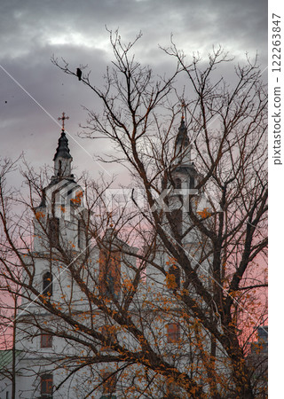 at dawn a raven sits on an autumn tree against the backdrop of a church in Minsk. 122263847