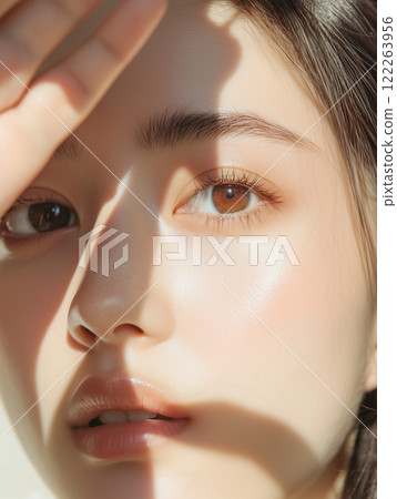 A beauty and fashion photoshoot shot with a close up of half the face of a beautiful young Asian woman with fair skin. 122263956