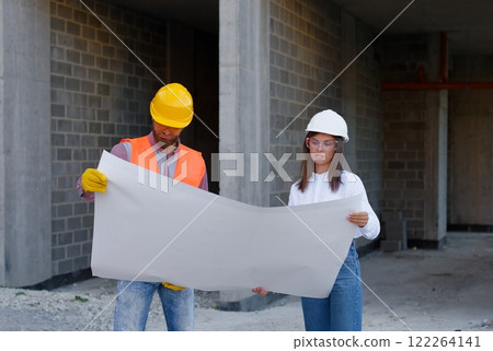 Construction workers examining blueprint on site 122264141