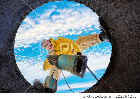 Bottom view of man immersing sewage pump into septic tank. 122264213