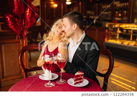 Couple in love exchanges gifts. Handsome man and woman on a date in a restaurant. Concept of love. 122264356