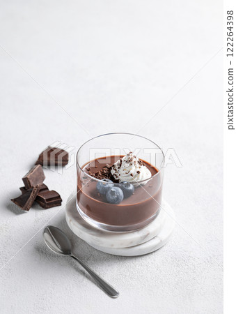 Chocolate pudding in a glass with whipped cream and fresh blueberry on a light background Chocolate pudding in a glass with whipped cream and fresh blueberry on a light background 122264398