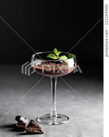 Chocolate pudding in a tall glass with mint and fresh blueberry on a dark background Chocolate pudding in a tall glass with mint and fresh blueberry on a dark background 122264400