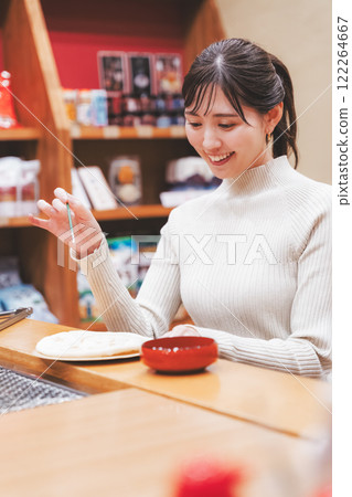 A young woman trying out hand-baked rice crackers [Photo courtesy of Niigata Rice Crackers premium SENBEI DEN] 122264667