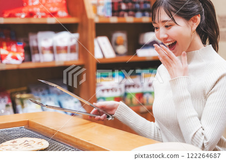 A young woman trying out hand-baked rice crackers [Photo courtesy of Niigata Rice Crackers premium SENBEI DEN] 122264687