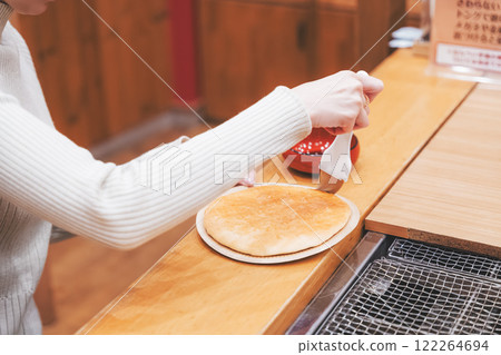A young woman trying out hand-baked rice crackers [Photo courtesy of Niigata Rice Crackers premium SENBEI DEN] 122264694