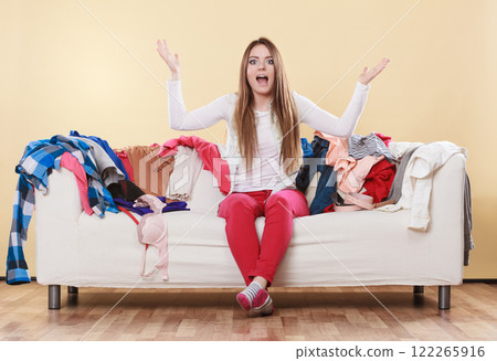 Helpless woman sitting on sofa in messy room home. Helpless woman sitting on sofa in messy room home. 122265916