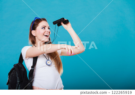 Tourist woman looking through binoculars on blue Tourist woman looking through binoculars on blue 122265919