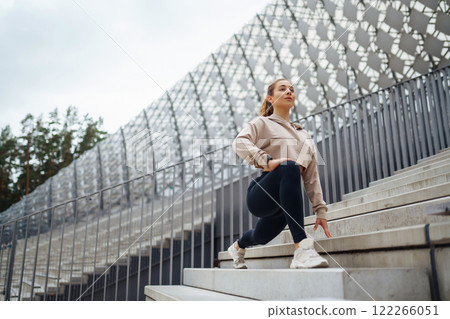 Active lifestyle. Young fitness woman exercising and stretching outdoors. Sports, sports training. 122266051