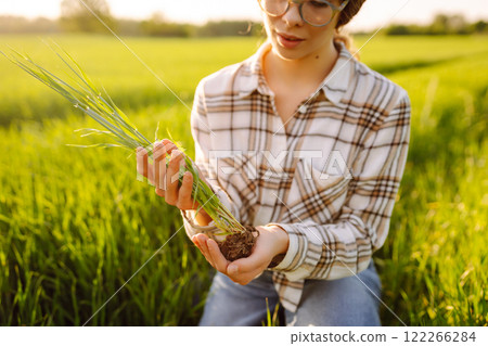 A woman agronomist checks the quality of new plants. Concept of gardening, ecology. A woman agronomist checks the quality of new plants. Concept of gardening, ecology. 122266284
