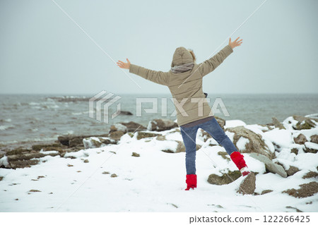 Woman on the shore of a snowy sea. Foggy winter 122266425