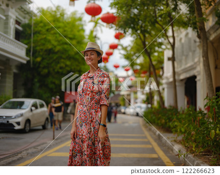 Young woman in ethnic dress and hat exploring the festive streets of George Town, Malaysia, during Chinese New Year. Vibrant lanterns, cultural celebrations, and historic charm create a unique 122266623