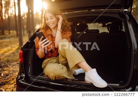 Beautiful woman in the trunk of a car enjoying nature in the forest. Adventure, technology concept. Beautiful woman in the trunk of a car enjoying nature in the forest. Adventure, technology concept. 122266777