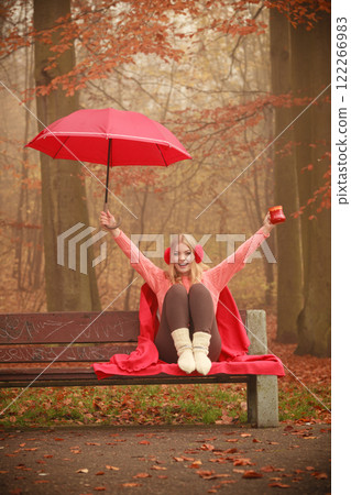 Girl in autumn park enjoying hot drink 122266983