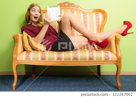 Amazed woman laying on sofa with pc tablet. 122267002