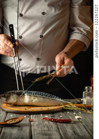 A skilled chef skillfully seasons a whole fish with aromatic herbs, surrounded by rustic kitchen tools. The warm ambiance enhances the culinary artistry in this vibrant scene A skilled chef skillfully seasons a whole fish with aromatic herbs, surrounded by rustic kitchen tools. The warm ambiance enhances the culinary artistry in this vibrant scene 122267227