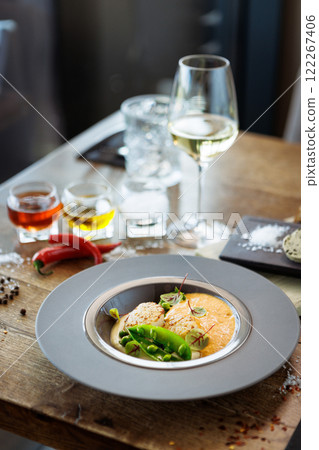 Scallops with shrimp foam, cauliflower cream and green peas on a plate. Delicious healthy seafood closeup served for lunch on a table in modern gourmet cuisine restaurant 122267406