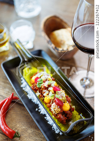 Beef tartare from Black Angus. Egg yolk, pickled cucumber, shallot, pearl onion, coriander and mustard seeds. Delicious healthy Italian food served for lunch in modern gourmet cuisine restaurant 122267412