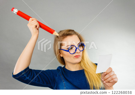 Confused woman holds big pencil note paper in hand Confused woman holds big pencil note paper in hand 122268038